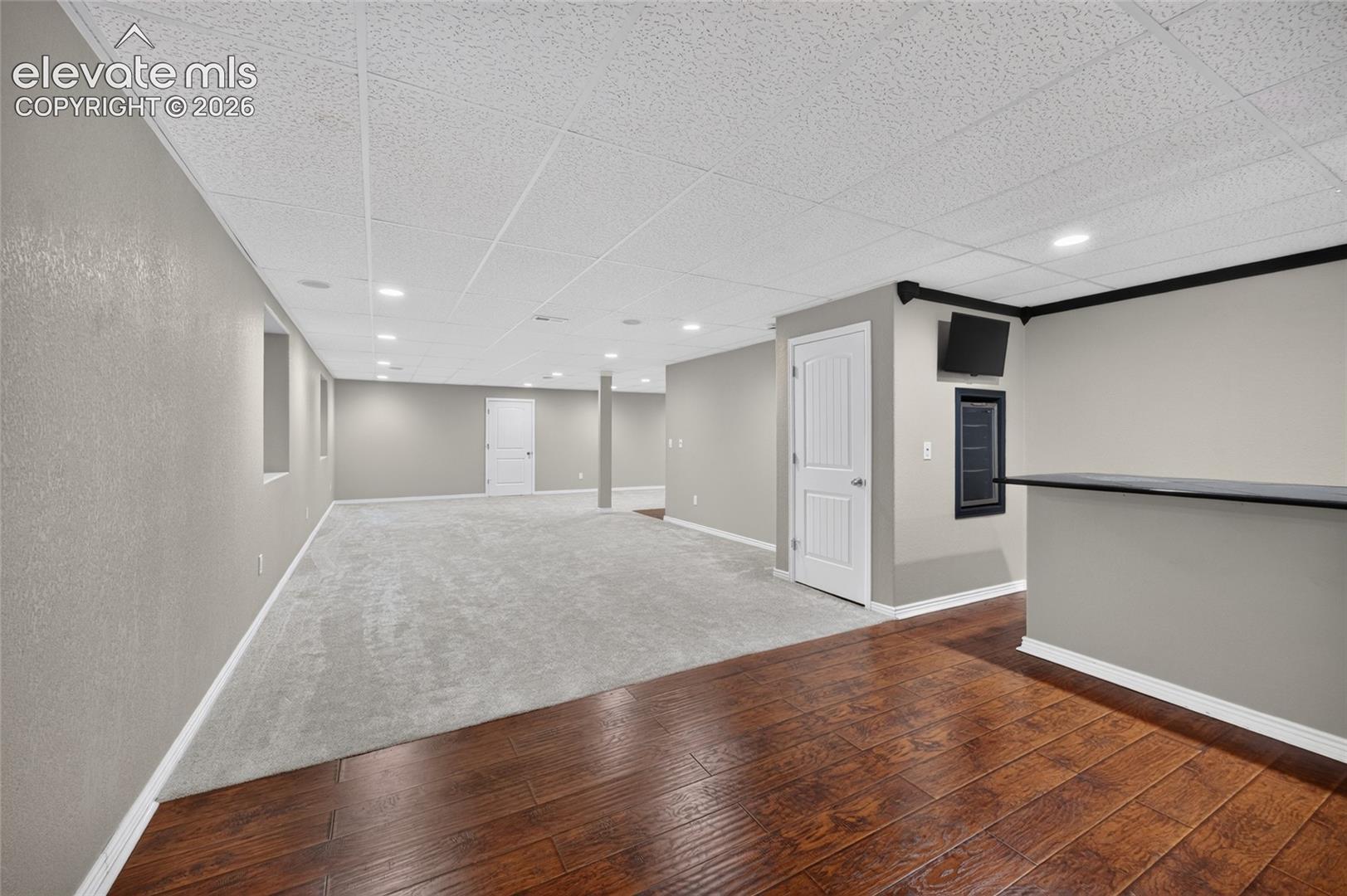 Open-concept area featuring a built-in wet bar, recessed lighting, drop ceiling, wood-finish flooring, and wall-to-wall carpeting