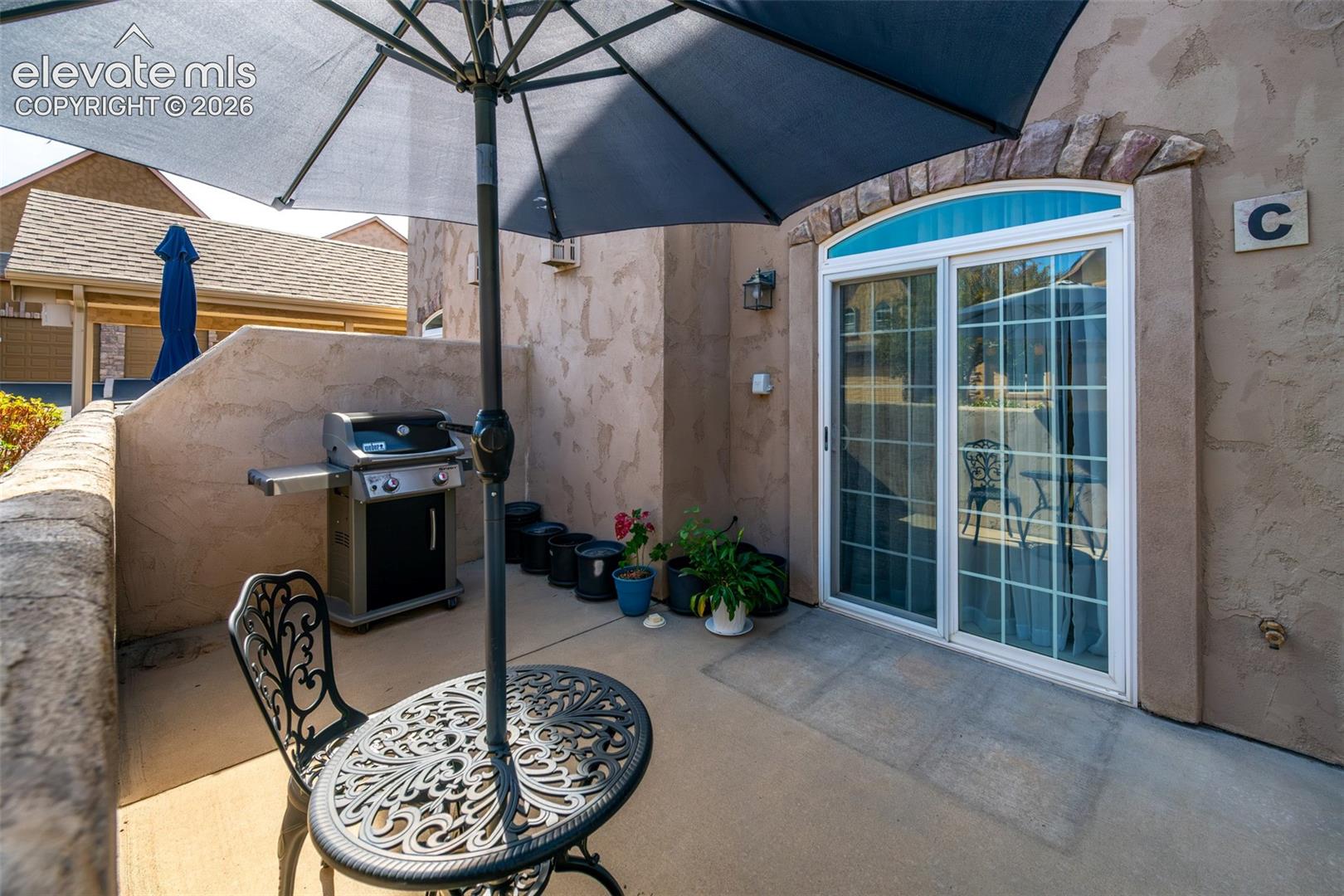 Private patio space with a sliding glass door entry, arched transom window, and stone accent trim