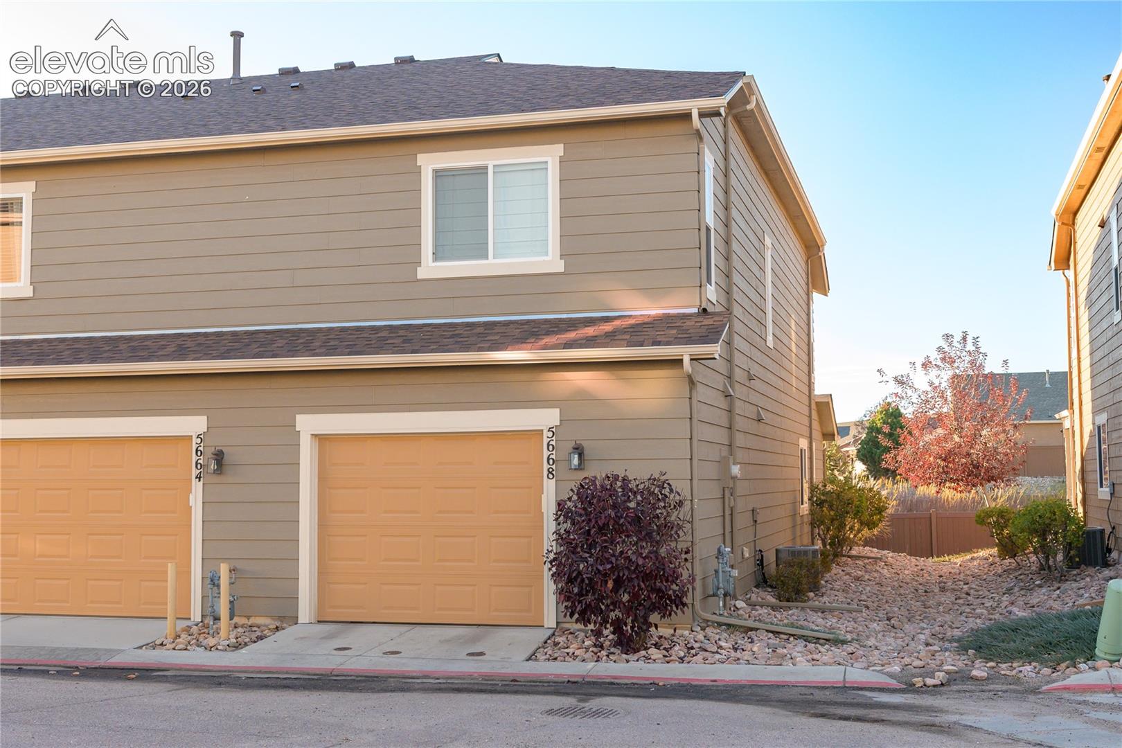 Two-story exterior featuring horizontal lap siding, an asphalt shingle roof, and attached garages with overhead doors