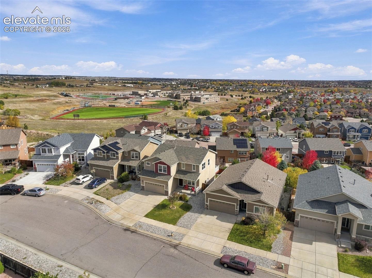 Aerial perspective of a suburban residential neighborhood featuring multi-story single-family homes with paved driveways, attached garages, and pitched rooflines