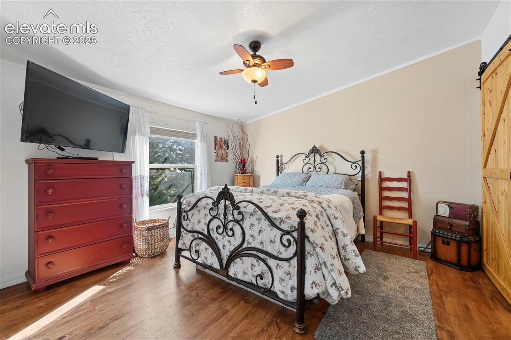 Wood-finish flooring, central ceiling fan with integrated lighting, and natural wood sliding barn door