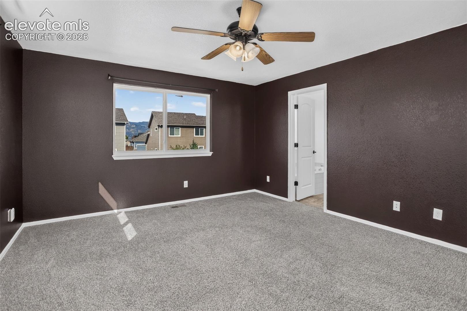 Neutral carpet flooring, a ceiling fan with integrated lighting, and a white-trimmed window