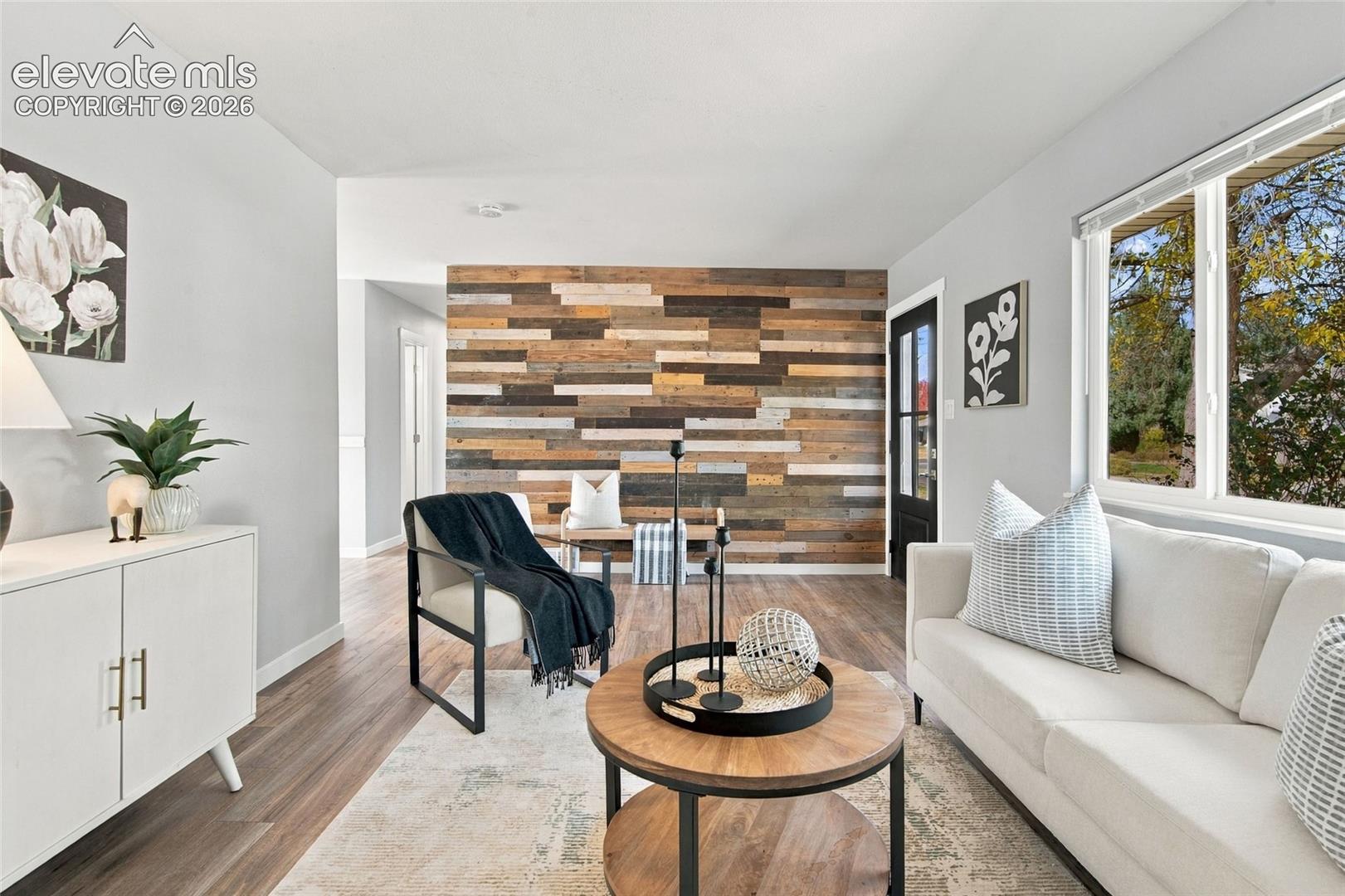 Living space featuring an accent wall with varied-tone wood-finish planks and wood-finish flooring