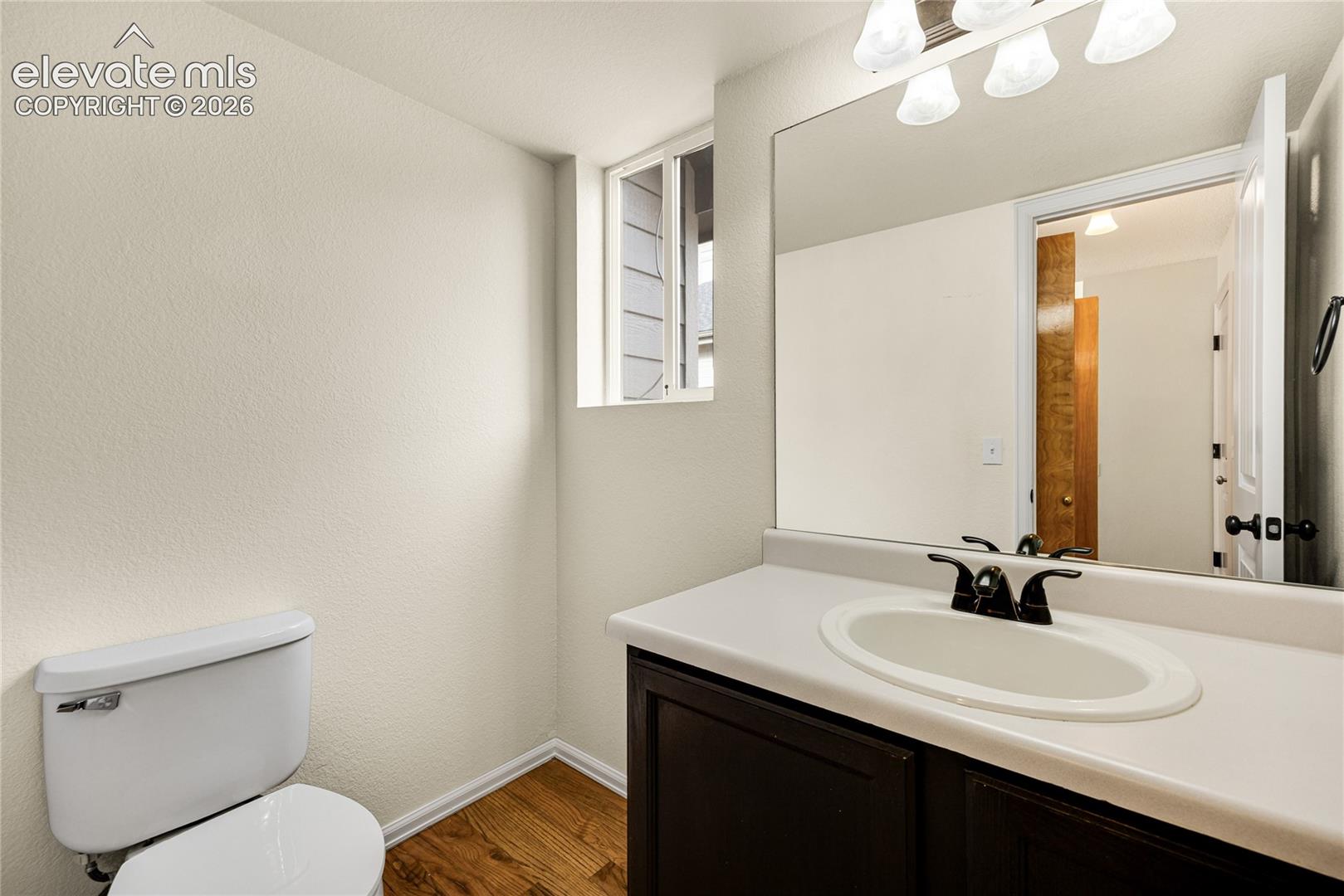 Dark cabinetry vanity with a light-toned countertop, integrated basin, matte black faucet, and a large wall-mounted mirror