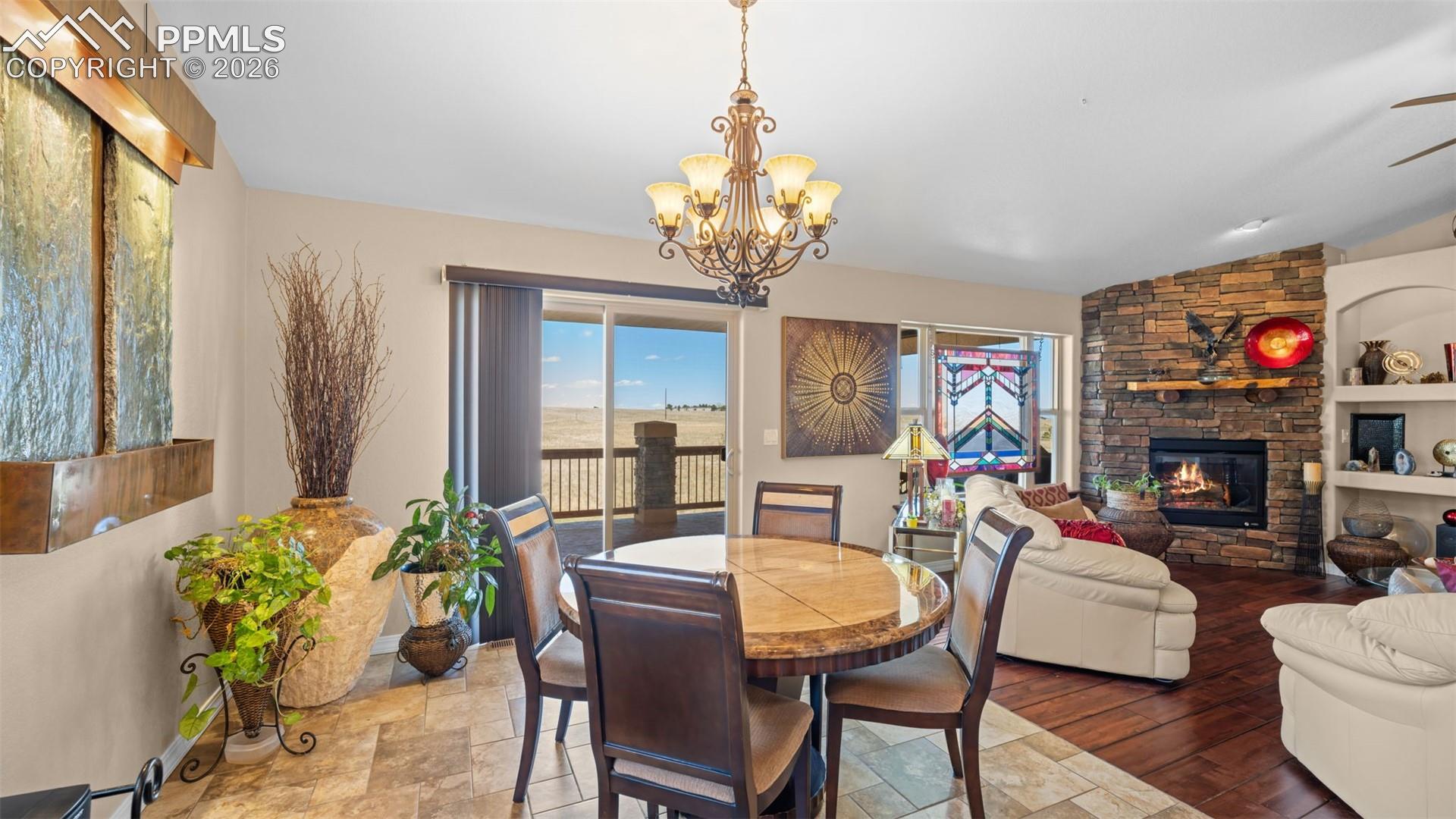 Dining area featuring a stone fireplace, plenty of natural light, suspended lighting, and lofted ceiling