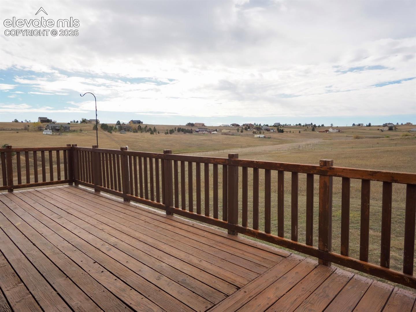 Elevated wood deck featuring a stained finish and perimeter wood railing, overlooking an expansive open landscape