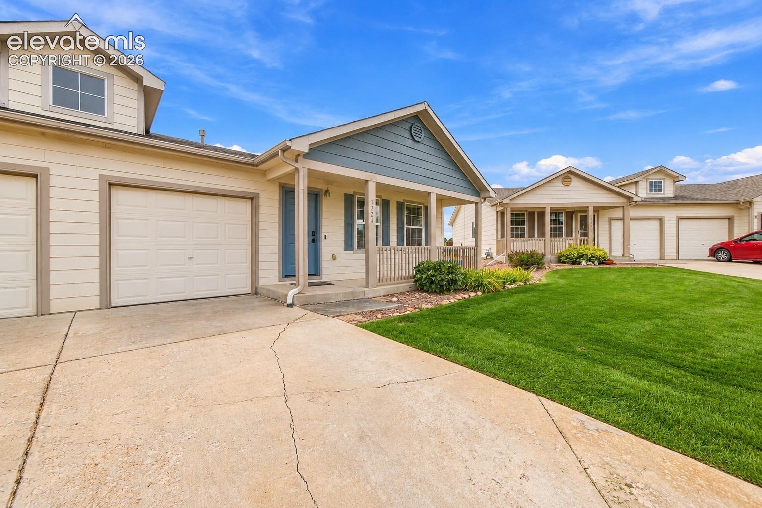 Siding exterior with a covered porch, attached garage, dormer window, and concrete driveway