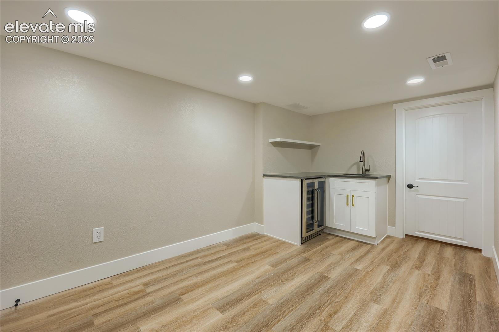 The basement, featuring a roomy den/living area, kitchenette, utility room with laundry, tankless hot water heater, and an additional lighted storage area.