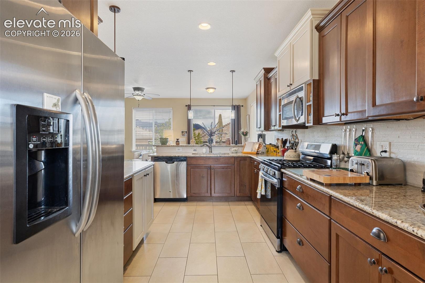 Kitchen featuring stainless steel appliances, granite countertops, tile flooring.