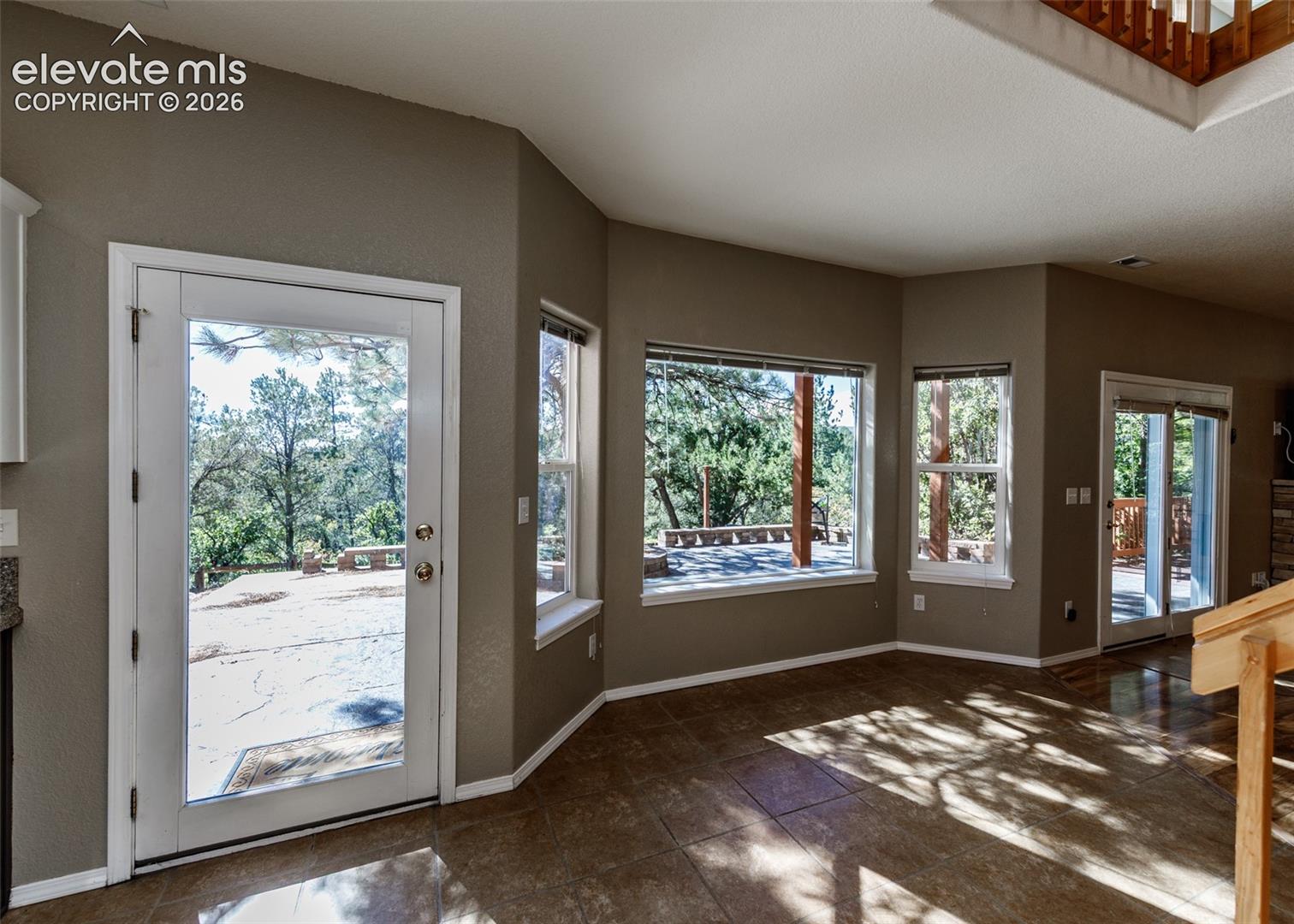 Side Entrance - Large-format tile flooring, multiple picture windows, full-lite glass entry door, and sliding glass door with external patio access