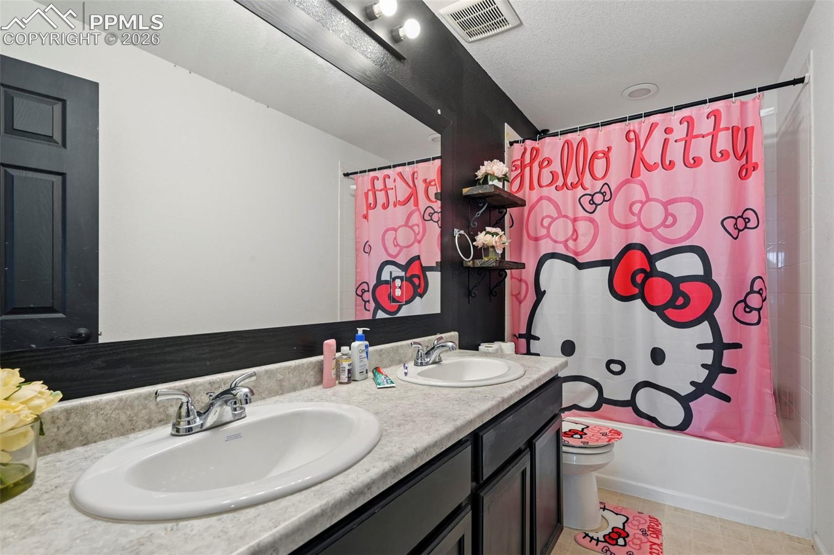 Bathroom featuring a dual-sink vanity with laminate countertop, integrated mirror, and built-in bathtub with shower