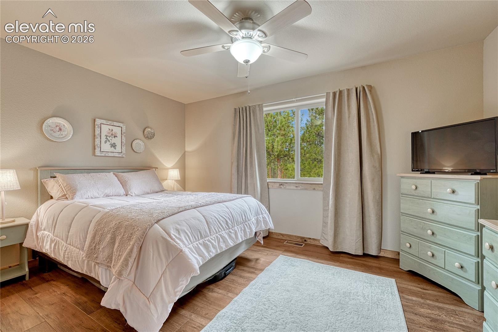 Wood-finish flooring, ceiling fan with integrated lighting, and window with natural wood trim