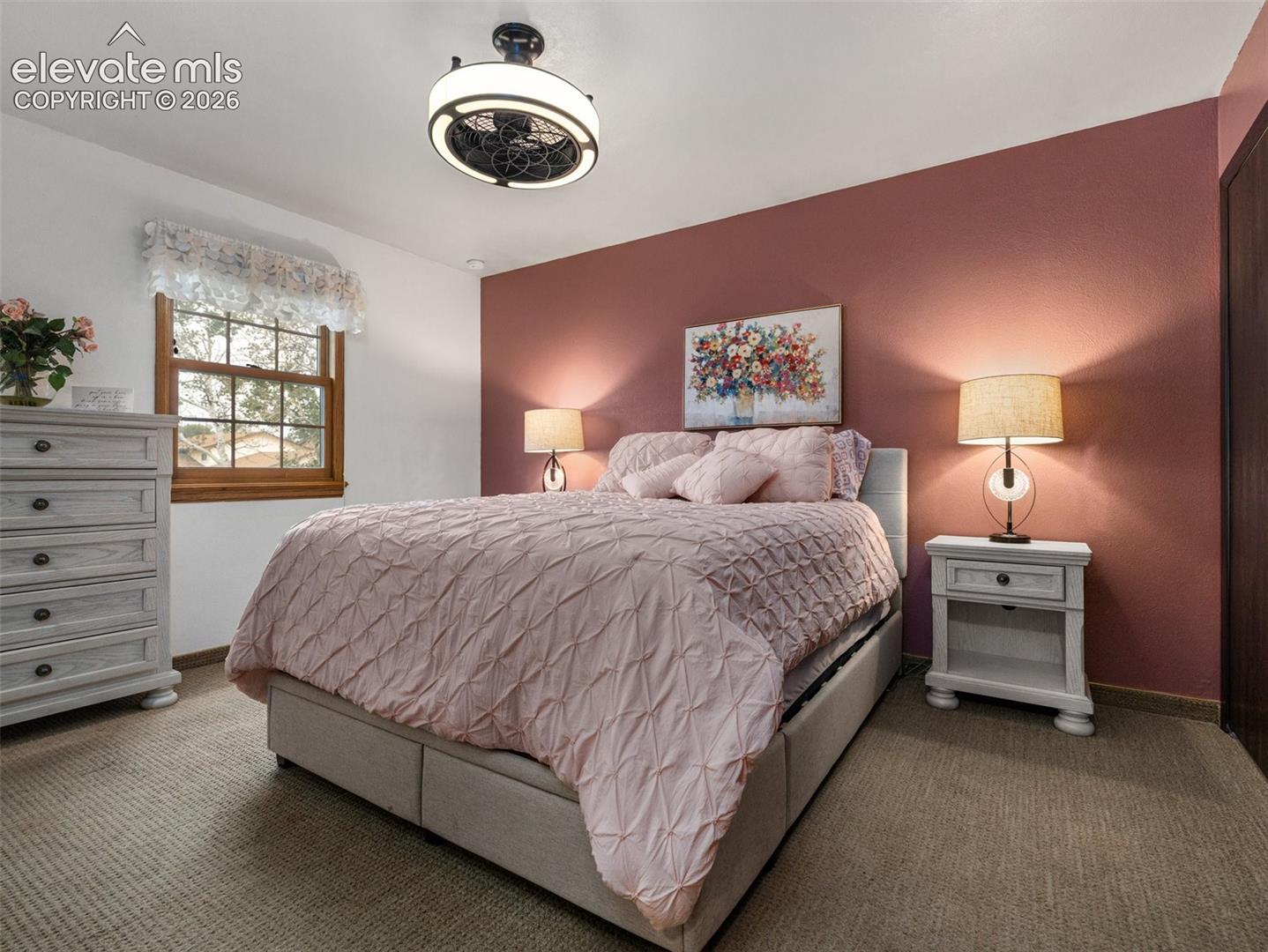 Ceiling fan with integrated lighting, wood-frame window, textured carpet, and a solid-core interior door