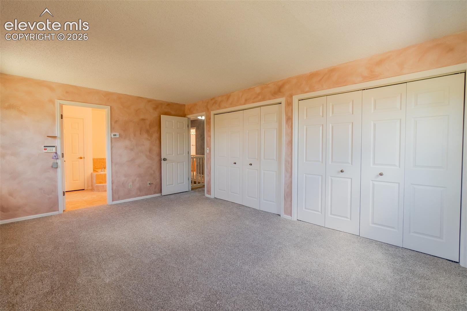 Plush carpeting, multiple bi-fold closet doors, and textured wall finishes