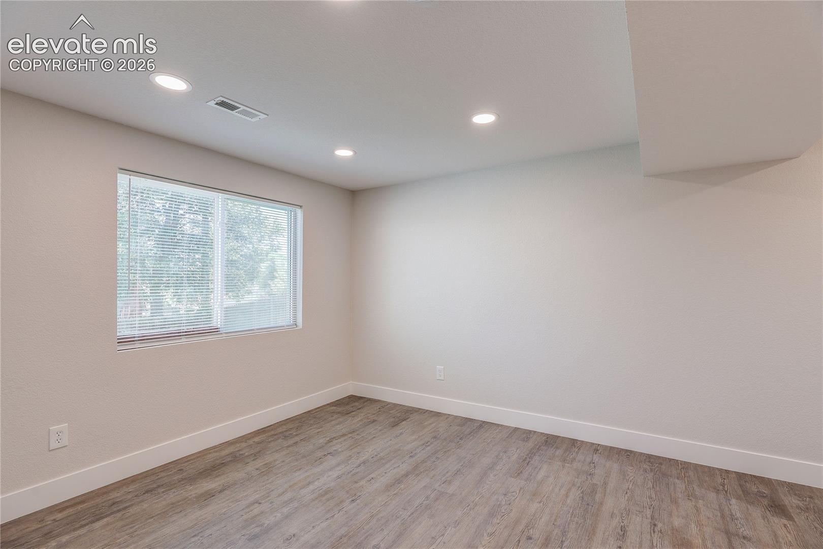 Neutral-toned interior space featuring wood-finish flooring, recessed lighting, and a large window