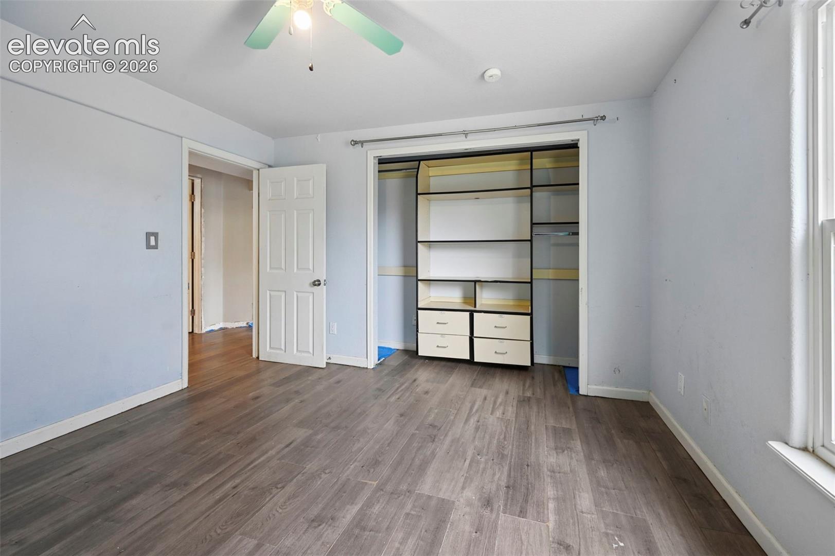 Room featuring wood-finish flooring, a ceiling fan with light fixture, and light blue wall tones