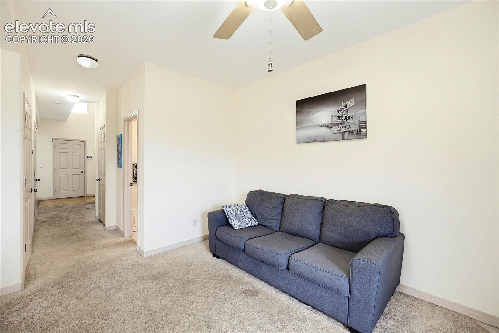 Carpeted room with a ceiling fan light fixture