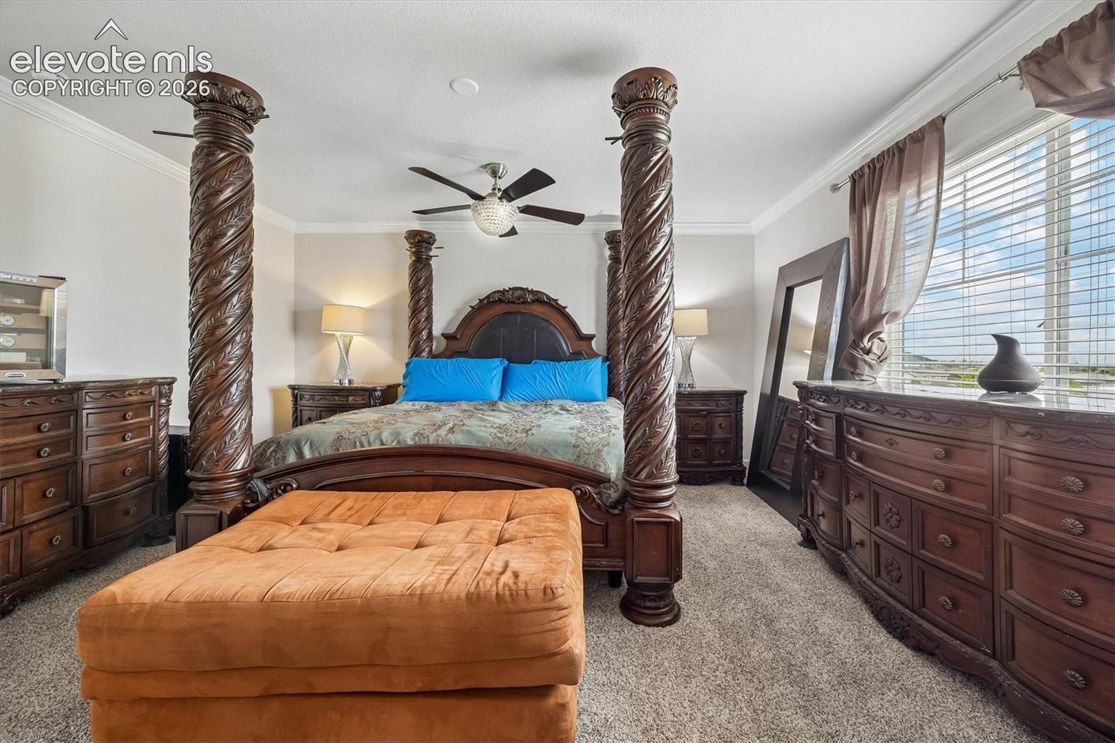 Carpeted bedroom featuring crown molding, a ceiling fan with integrated lighting, and window blinds