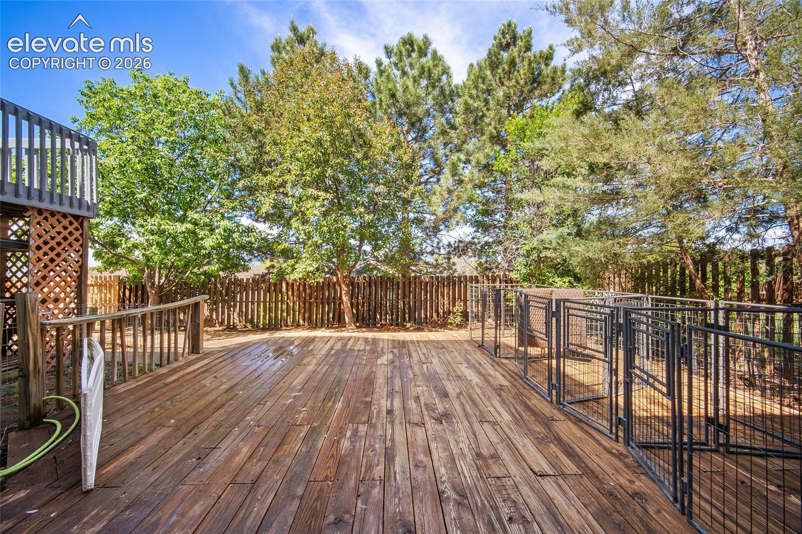 Spacious wood deck featuring a protective railing and integrated metal enclosures