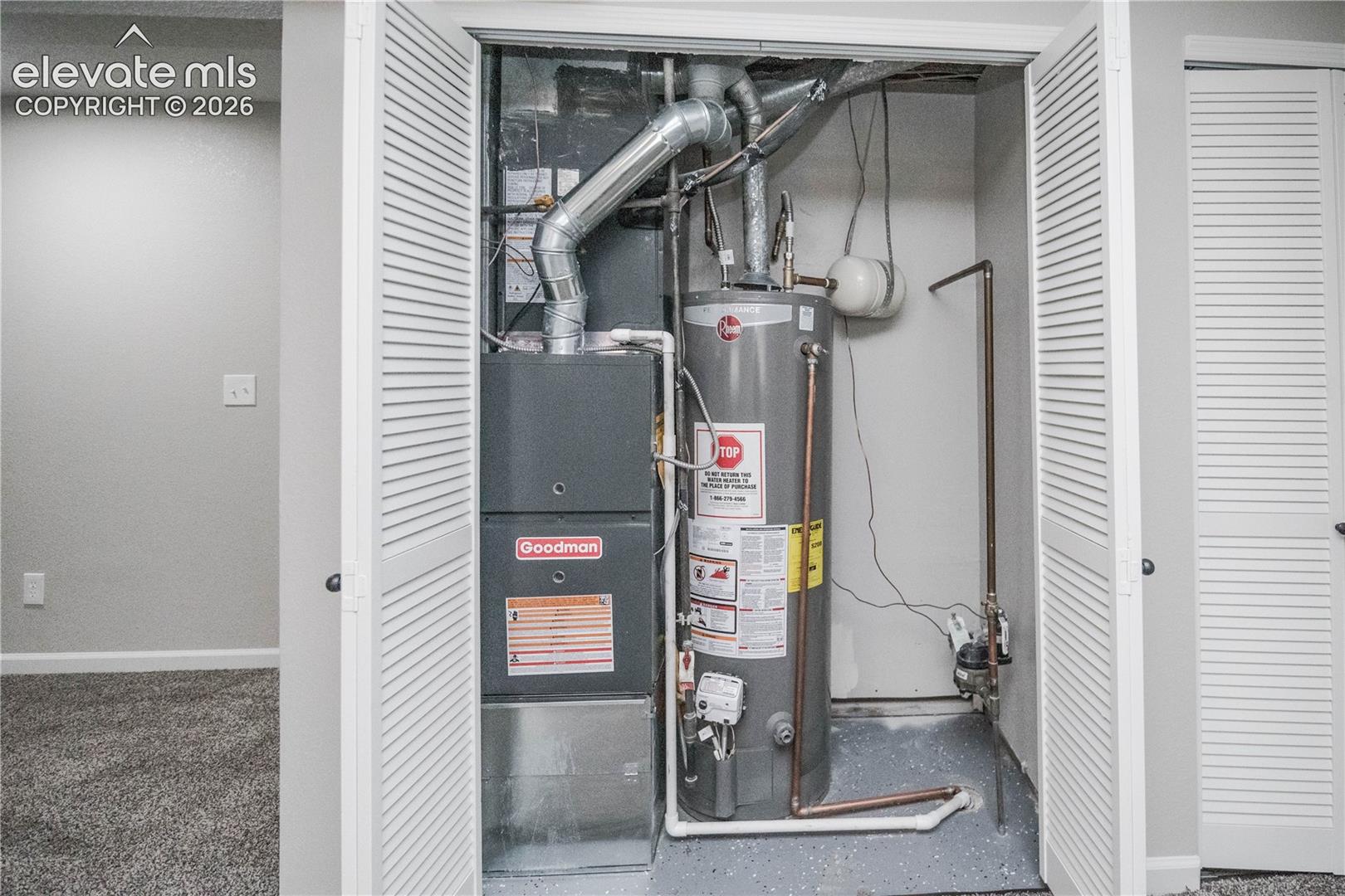 Utility closet featuring a Goodman furnace, water heater, and louvered double-door access