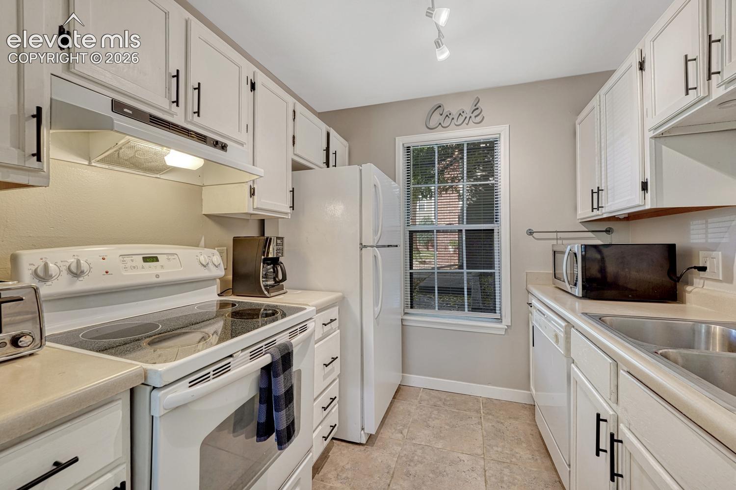 Kitchen featuring white cabinetry with black hardware, light-toned countertops, and tile flooring