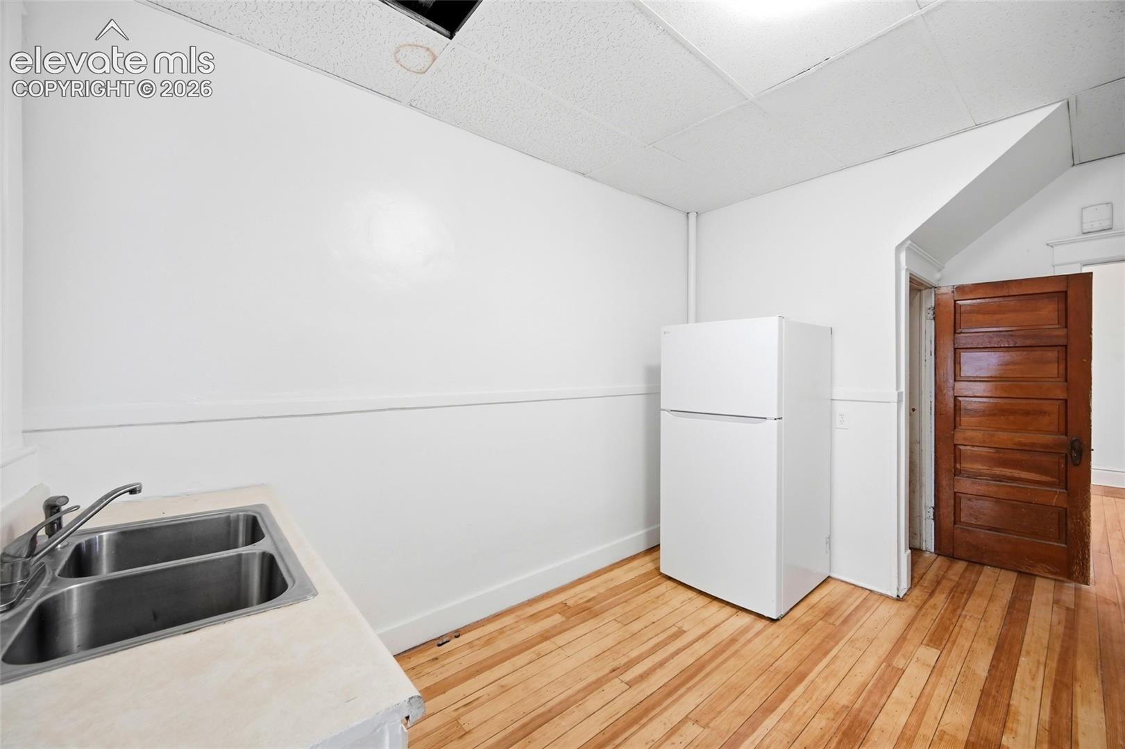 Wood-finish flooring, double-basin stainless steel sink, and a solid wood five-panel door