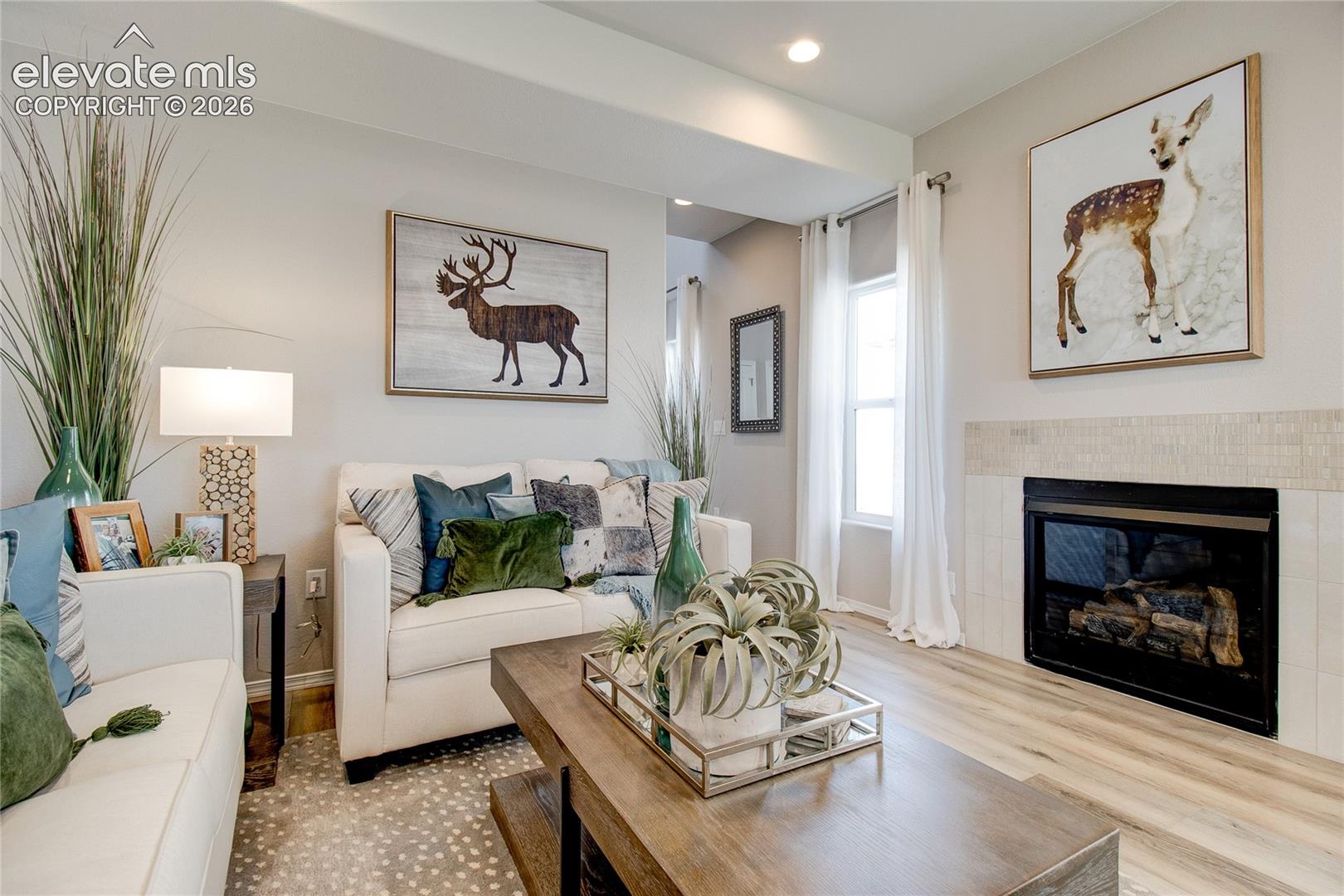 Living area featuring wood-finish flooring, a fireplace with a neutral tile surround, and recessed ceiling lighting