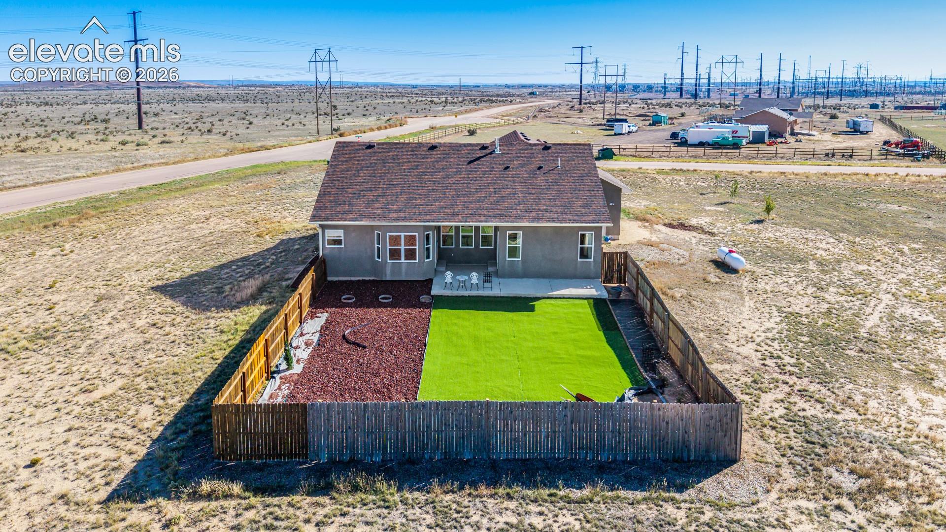 Fenced backyard featuring synthetic turf, decorative gravel ground cover, and a concrete patio