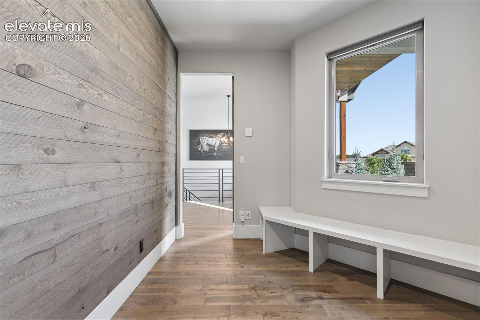 Wood-finish flooring, accent wall with horizontal wood planks, built-in window bench, and a large operable window