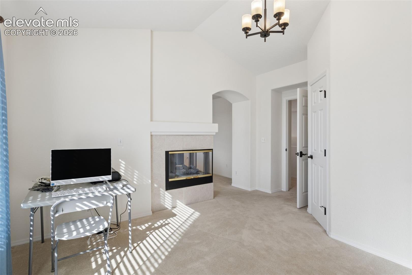 Master-primary bedroom with attached retreat/office room, vaulted ceilings, chandelier, and double-sided fireplace 