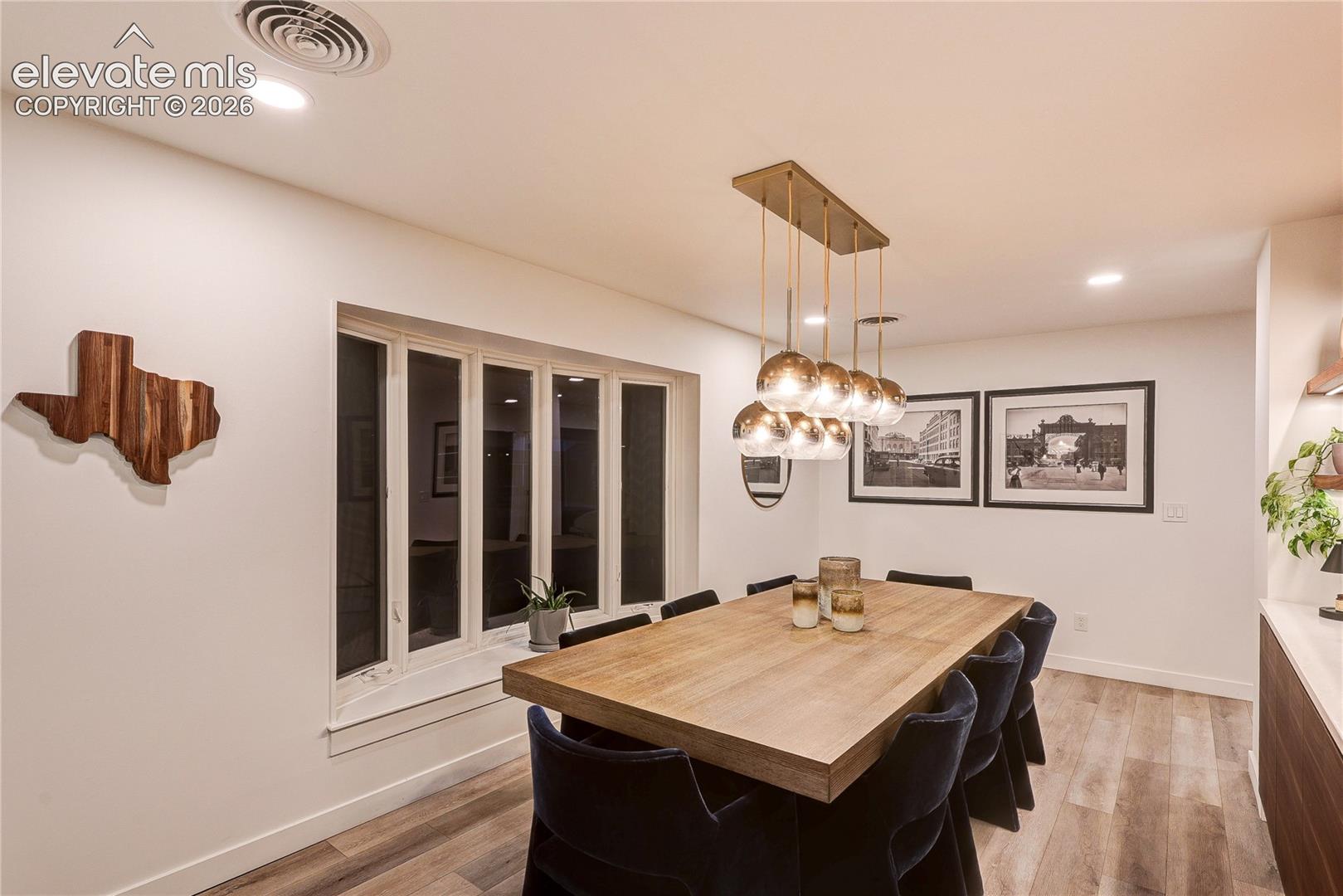 Dining area featuring wood-finish flooring, recessed lighting, a multi-light pendant fixture, and a built-in window
