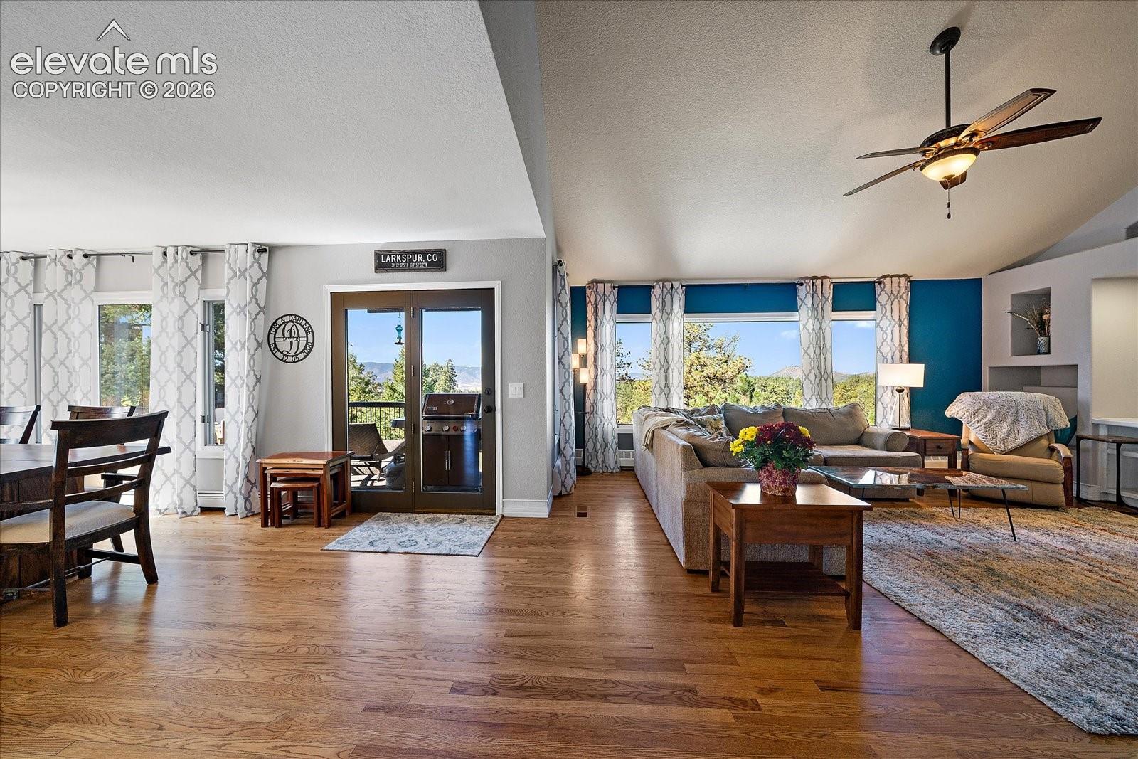Vaulted ceilings, wood-finish flooring, glass-paneled exterior door, built-in wall shelving, and ceiling fan