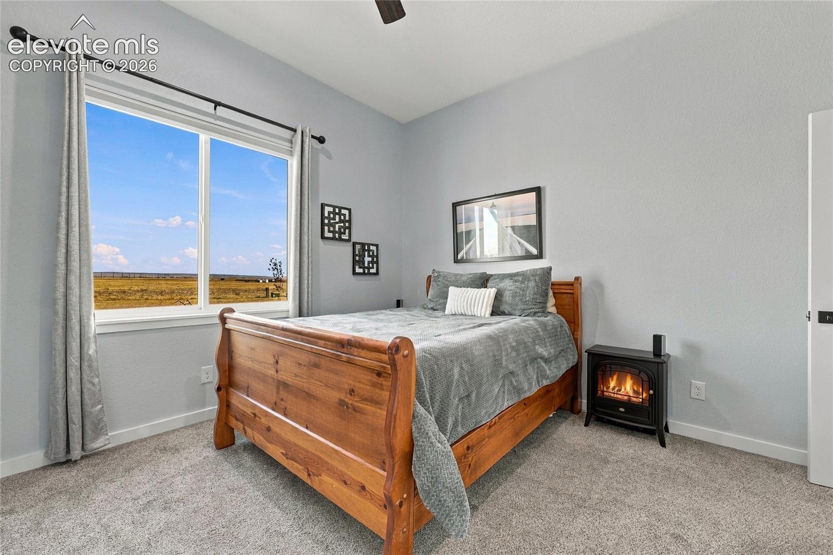 Neutral-toned interior featuring carpeting, a large window with natural light, and a black metal ceiling fan