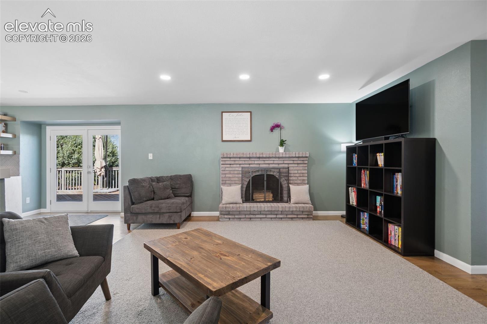 Living area featuring a floor-to-ceiling light brick fireplace, recessed lighting, double French doors, and built-in wall shelving
