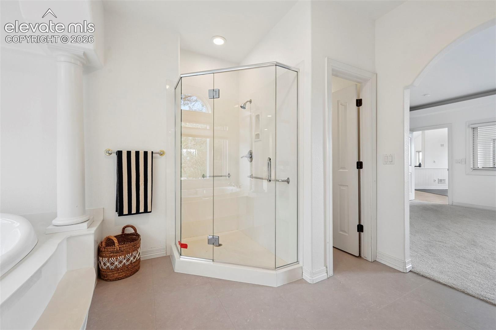 Corner glass-enclosed shower with chrome fixtures