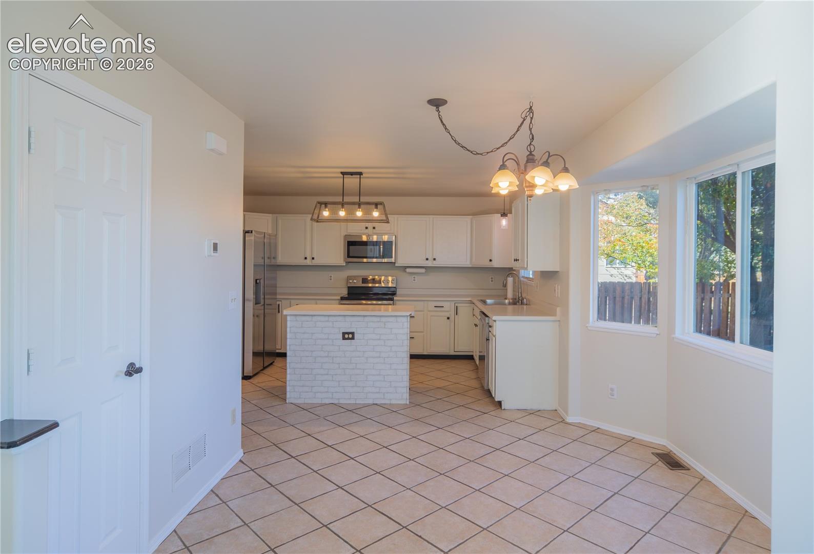 Bright, open kitchen and dining area with tile flooring, center island, and plenty of natural light.