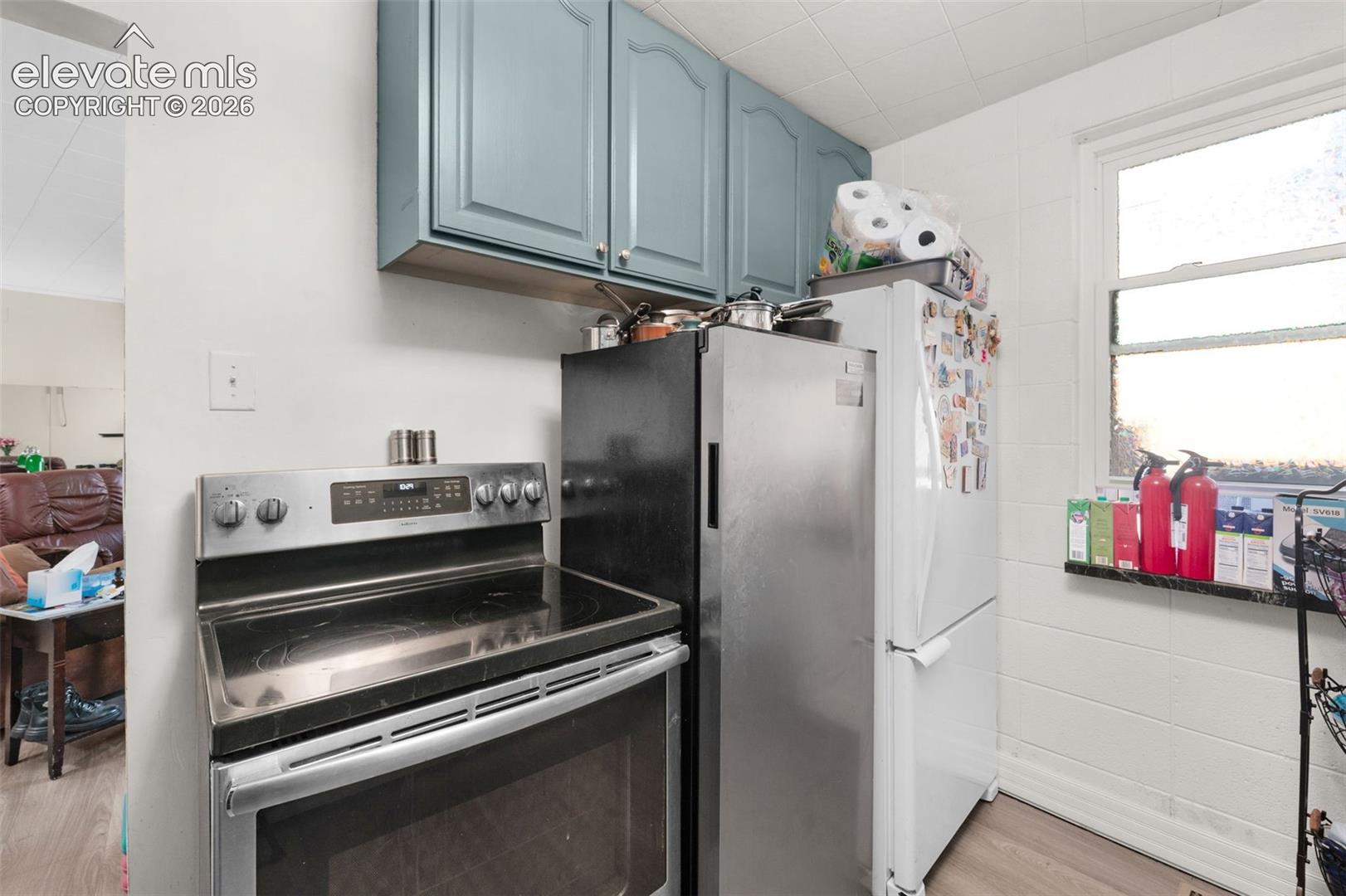Kitchen featuring blue-painted upper cabinetry, stainless steel electric range, and a dual-refrigerator configuration