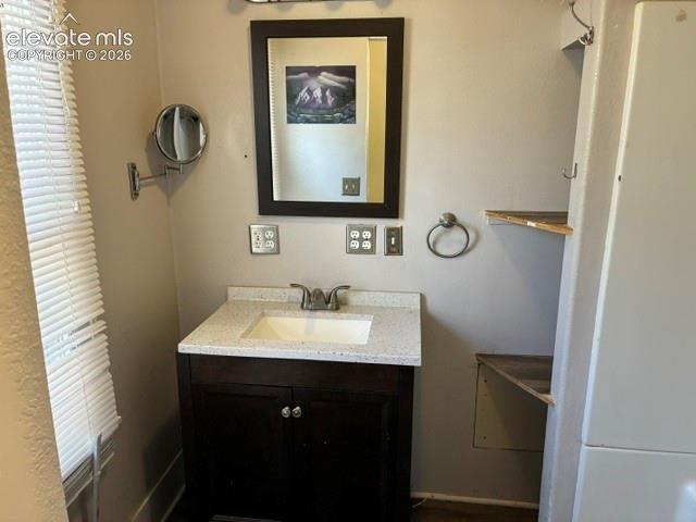 Bathroom vanity featuring a dark wood-finish cabinet with double doors, a white integrated sink, and a speckled countertop