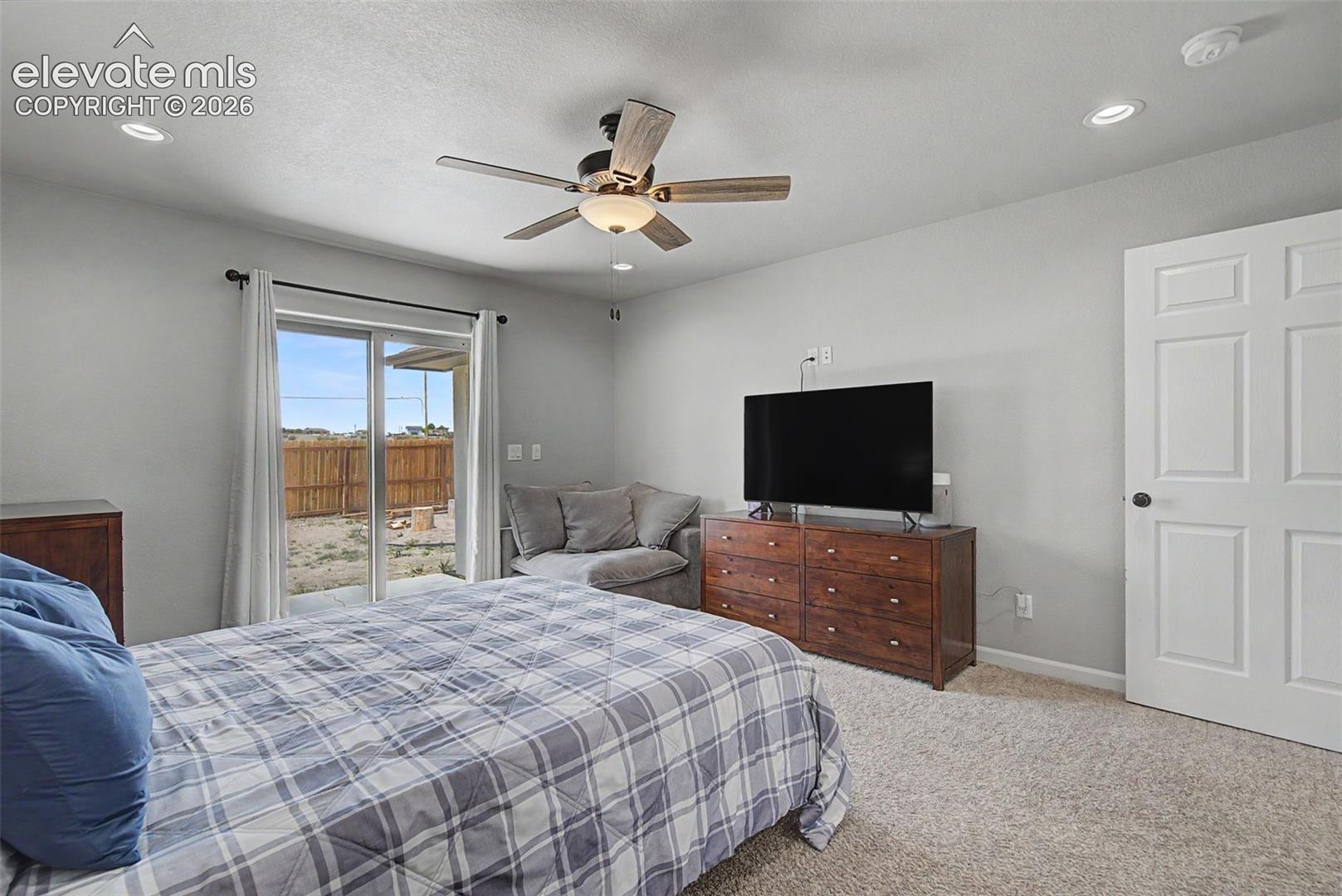 Carpeted room featuring a ceiling fan with integrated lighting, recessed lighting, and a paneled interior door