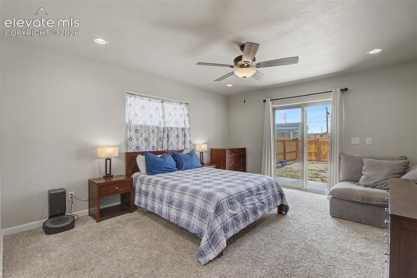 Spacious bedroom featuring light-colored walls, recessed lighting, and a ceiling fan