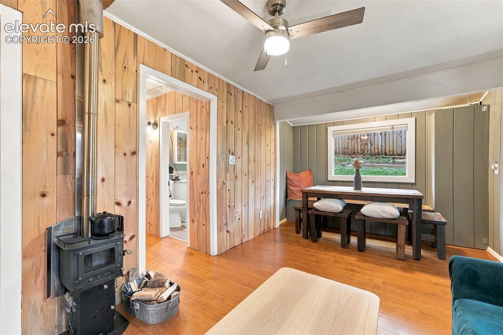 Interior dining and living space featuring wood paneling, a metal wood-burning stove.