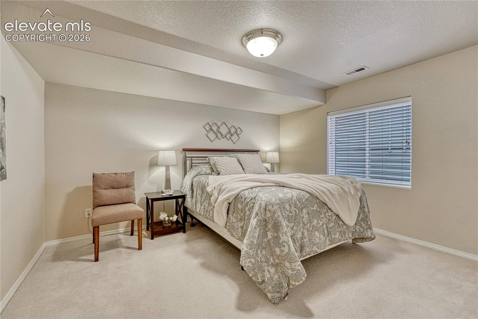 The generous basement guest bedroom features an egress window, wall-to-wall carpet, and deep closet space
