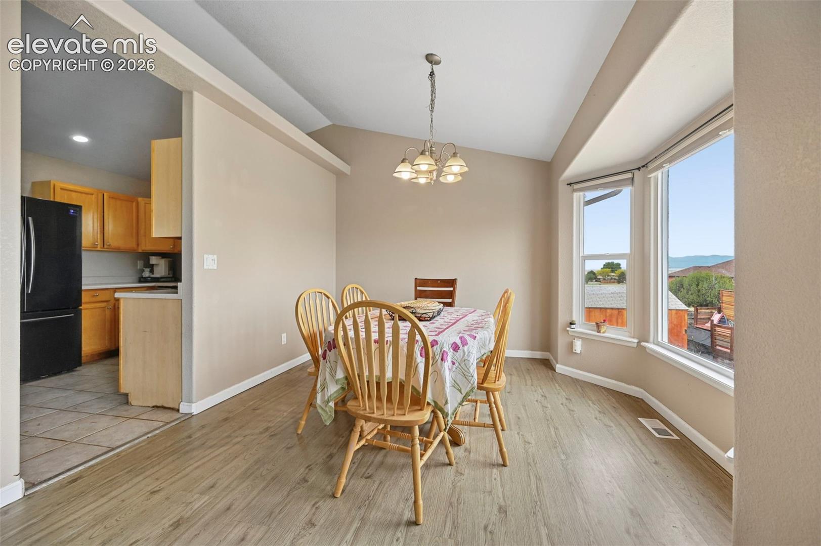 Dining area featuring wood-finish flooring, a vaulted ceiling, and a multi-light chandelier
