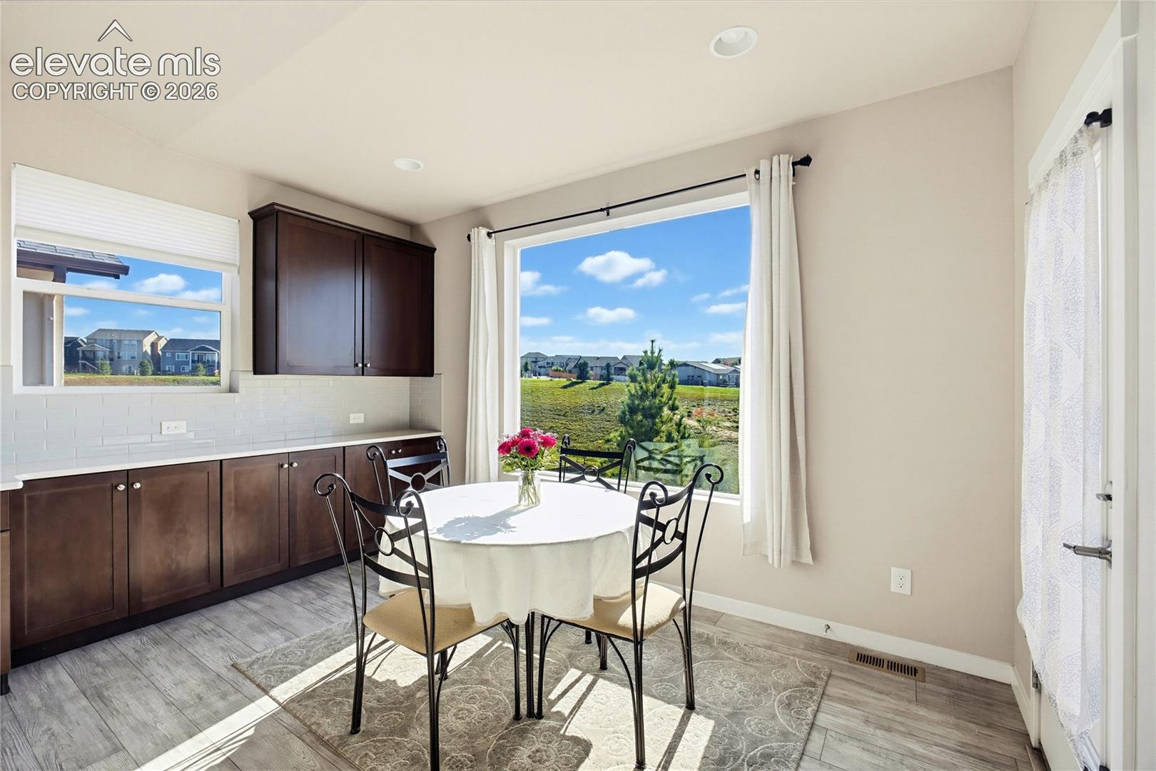 Custom cabinetry with stone-surface countertops, subway tile backsplash, recessed lighting, and large picture window