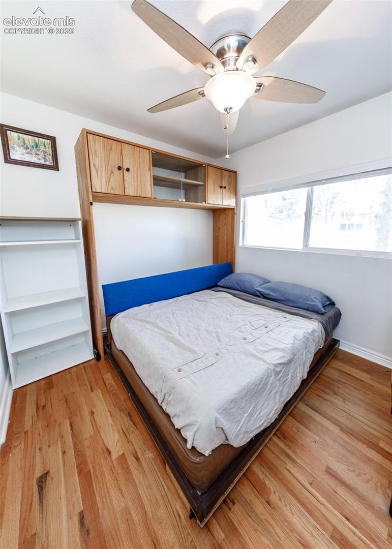 Hardwood flooring, built-in cabinetry, ceiling fan with integrated lighting, and multiple windows
