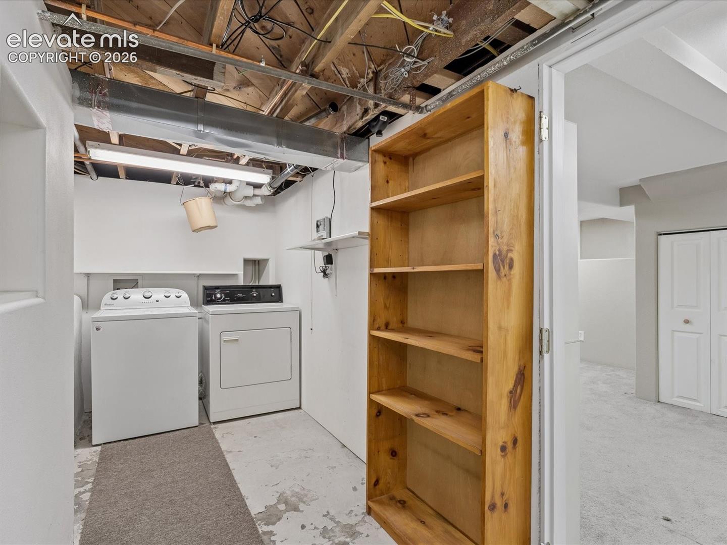 Dedicated laundry area with a washer and dryer, accompanied by a multi-shelf wooden bookcase