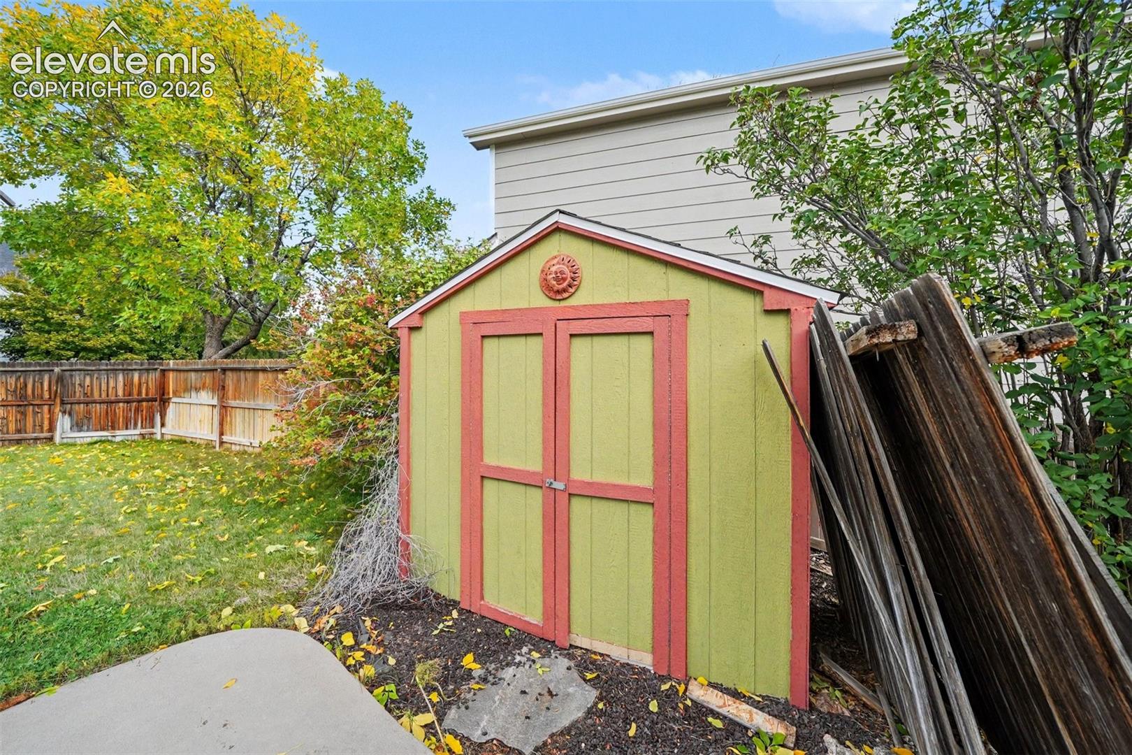 Exterior storage shed with double doors, wood-paneled siding, and concrete hardscaping