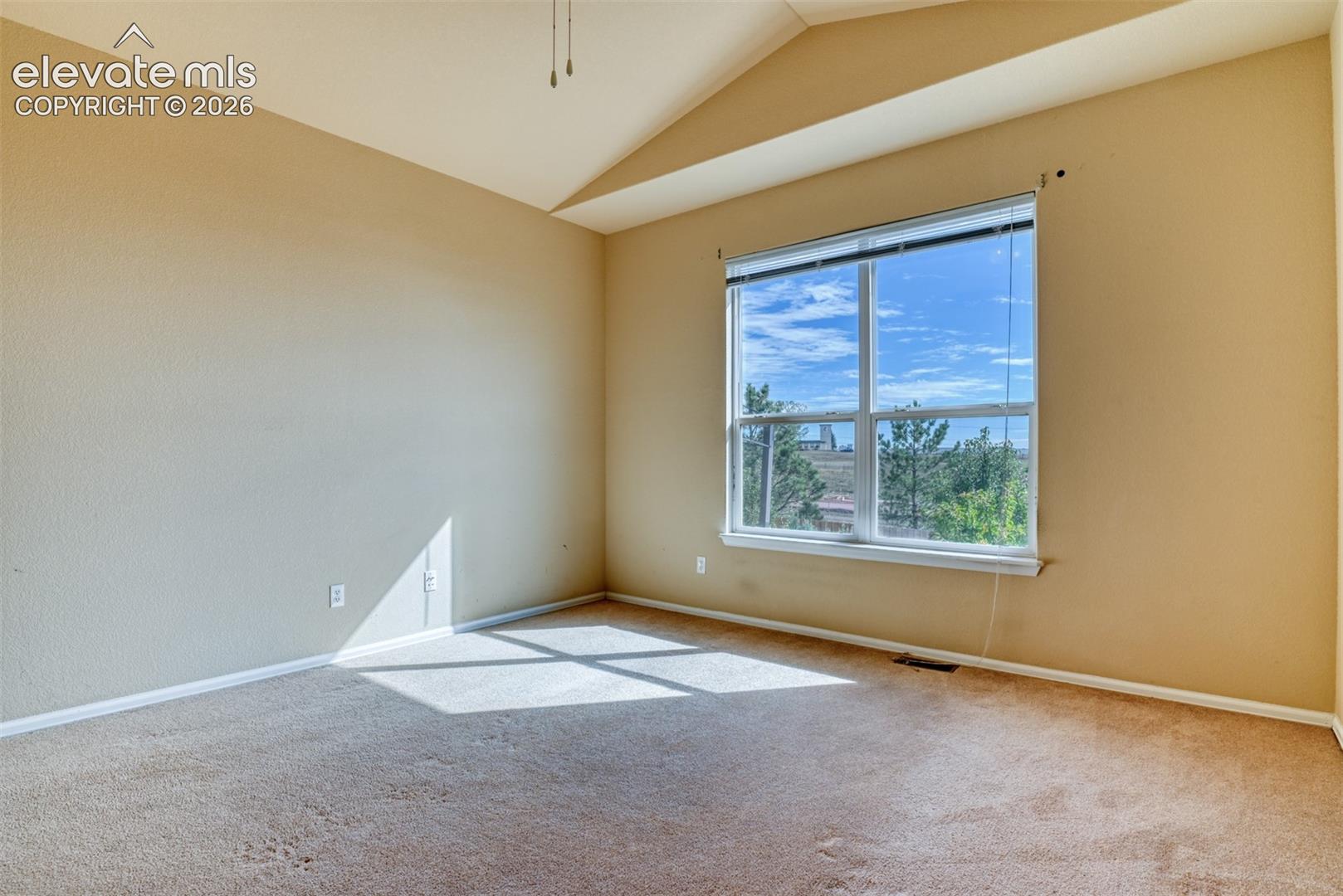 Vaulted ceiling featuring a ceiling fan, neutral wall paint, carpeting, and a double-pane window