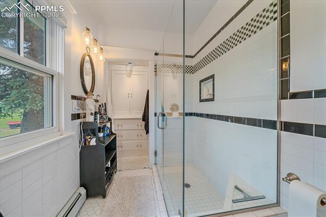Bathroom with a stall shower, a baseboard heating unit, tile walls, and tile patterned floors