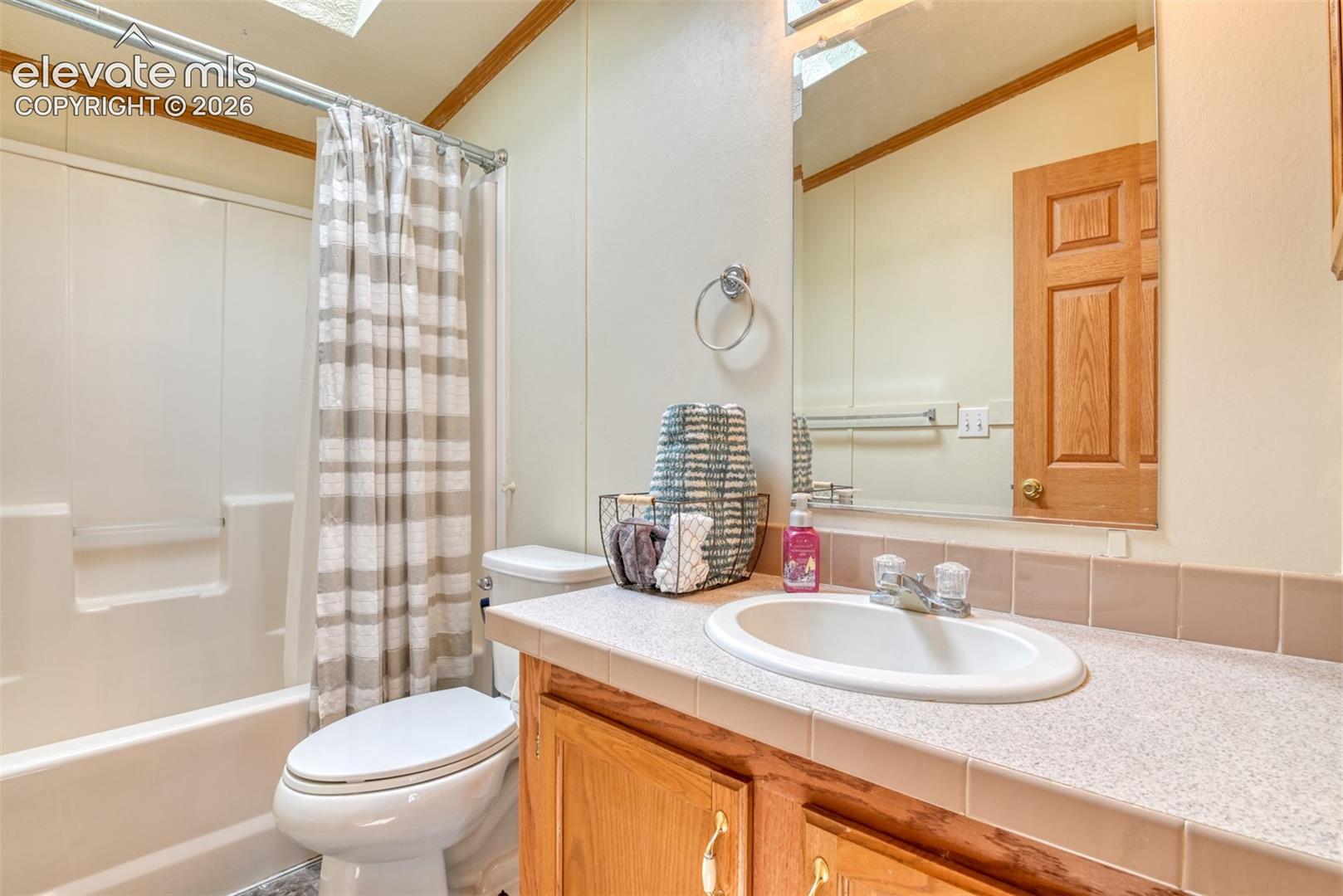 Bathroom with white tub and shower surround, light-colored vanity with integrated sink, and a large wall-mounted mirror
